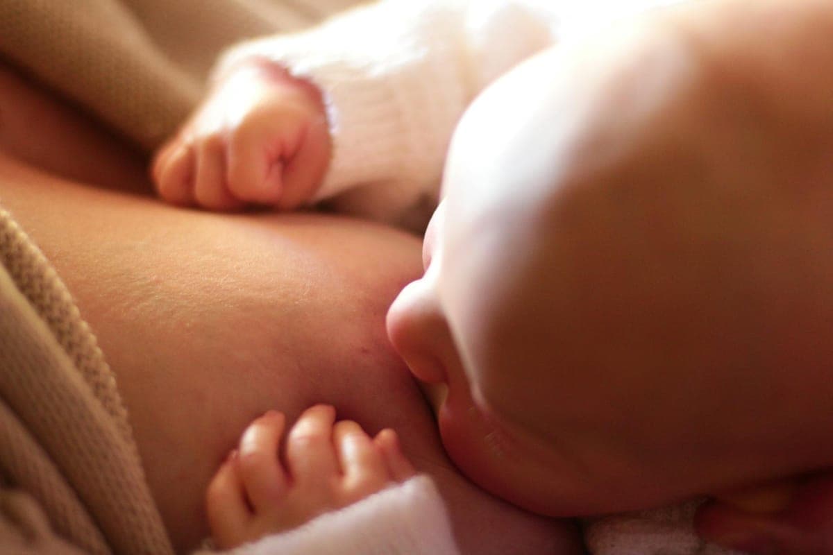 New mum sitting comfortably with a healthy balanced meal while breastfeeding her baby