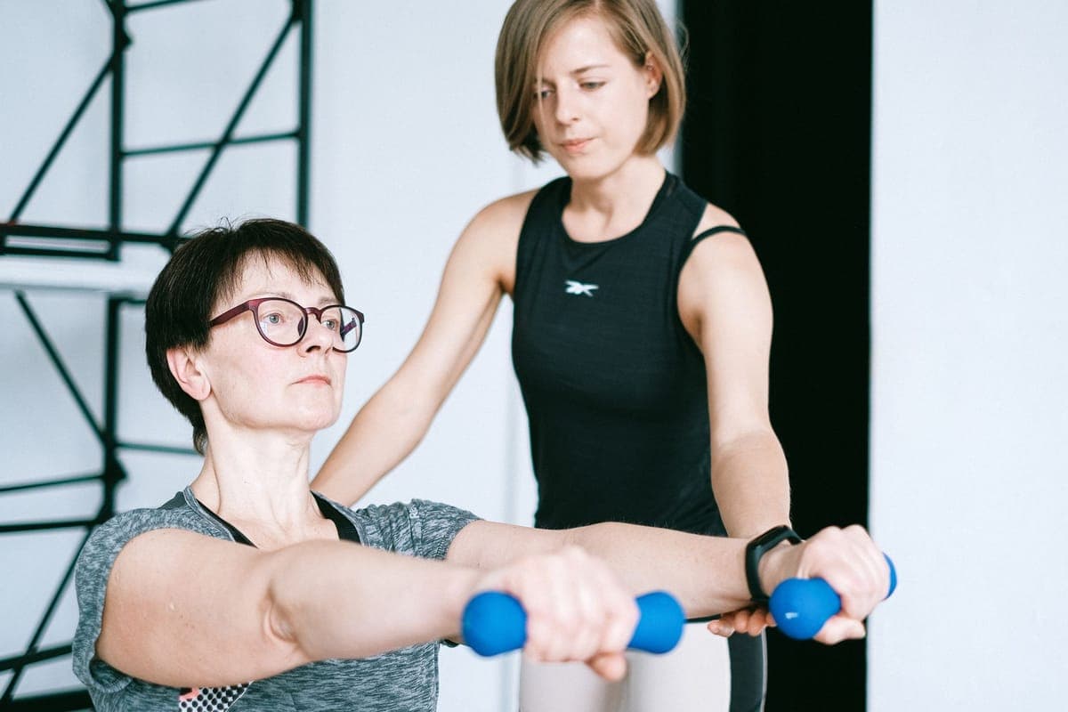 Woman in her late forties lifting dumbbells at home during perimenopause
