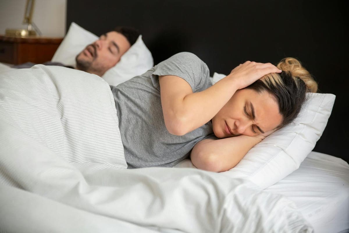 Woman struggling to sleep at night in a dimly lit bedroom, representing perimenopausal sleep disturbance