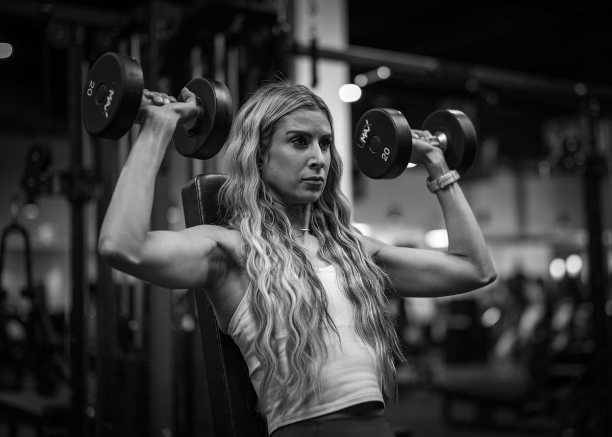 Woman in her forties doing resistance training with dumbbells at home