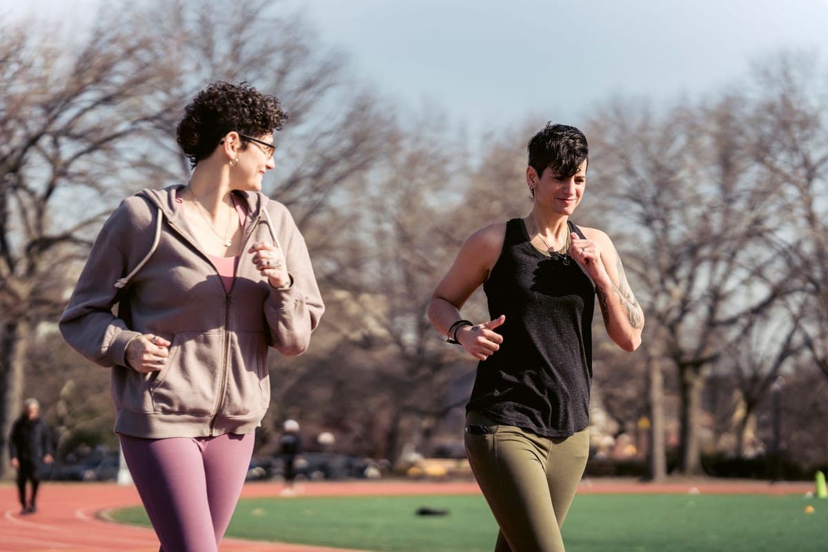 Mother in activewear jogging slowly on a path with a pram, illustrating a gradual return to postpartum running