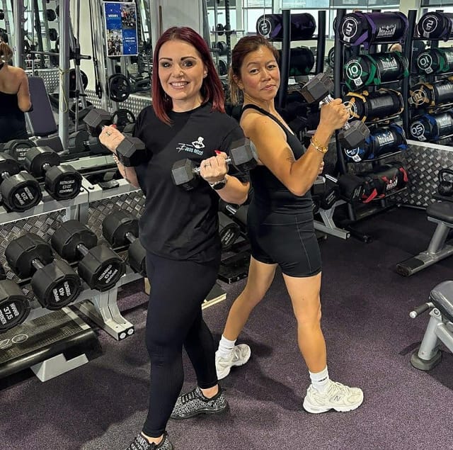 FitForHer coach demonstrating proper form in a home gym setting